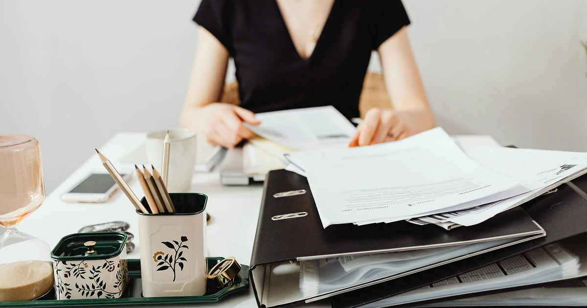 Professionnelle consultant un dossier de validation VAE sur un bureau en bois, illustrant la prise en charge des frais de jury et d'accompagnement par l'OPCO et le CPF
